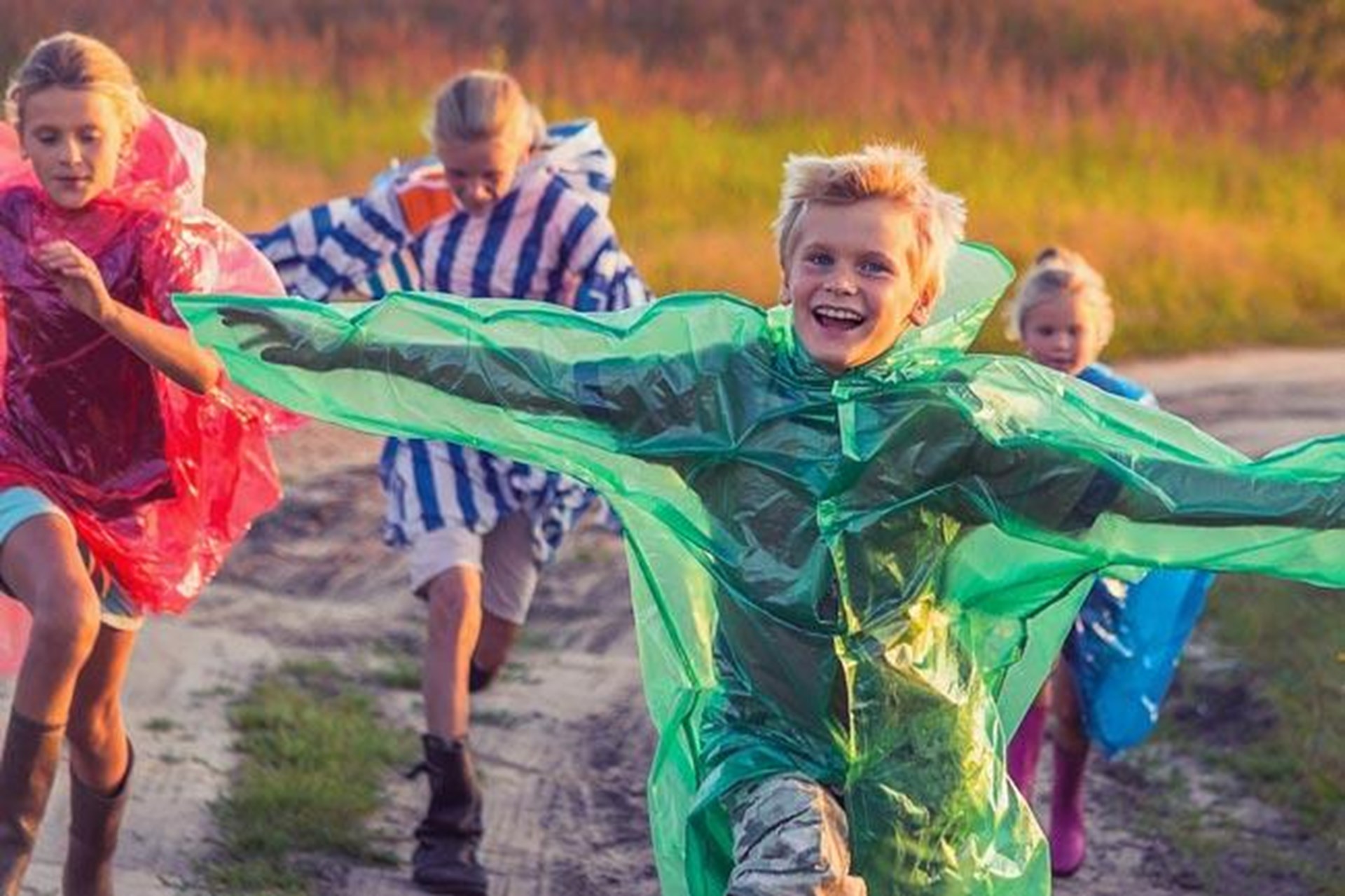 Fröhliche Kinder in bunten Regenponchos
